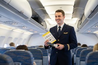 Steward homme souriant en uniforme navy dans l'avion